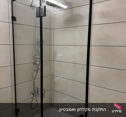מקלחון זכוכית עם מסגרת שחורה בחדר אמבטיה